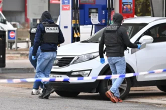 Getty Images Forensic officers examine evidence at the site of a petrol station where a gunman opened fire from a vehicle, killing one person and injuring four others, in Trappes.