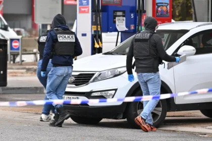 Getty Images Forensic officers examine evidence at the site of a petrol station where a gunman opened fire from a vehicle, killing one person and injuring four others, in Trappes.