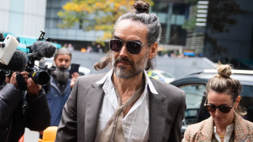 PA Russell Brand arrives at Southwark Crown Court, alongside his wife, wearing sunglasses and with his hair tied up, as cameras fix upon him