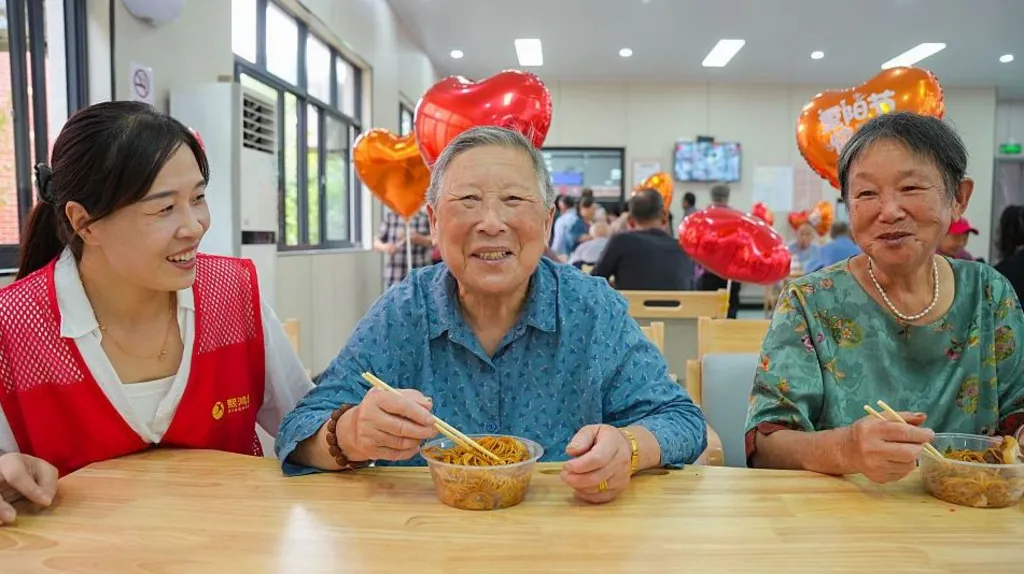VCG via Getty Images Elderly residents taste longevity noodles while volunteers accompany them at a community care center during the Double Ninth Festival, also known as Chongyang Festival, on October 18, 2026 in Huzhou, Zhejiang Province of China.