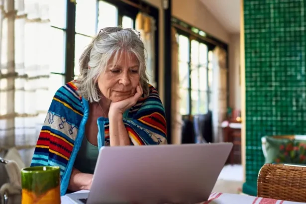 10000 hours Getty Images Old lady with grey hair sits at home with a brightly coloured blanket around her shoulders, looking at her laptop