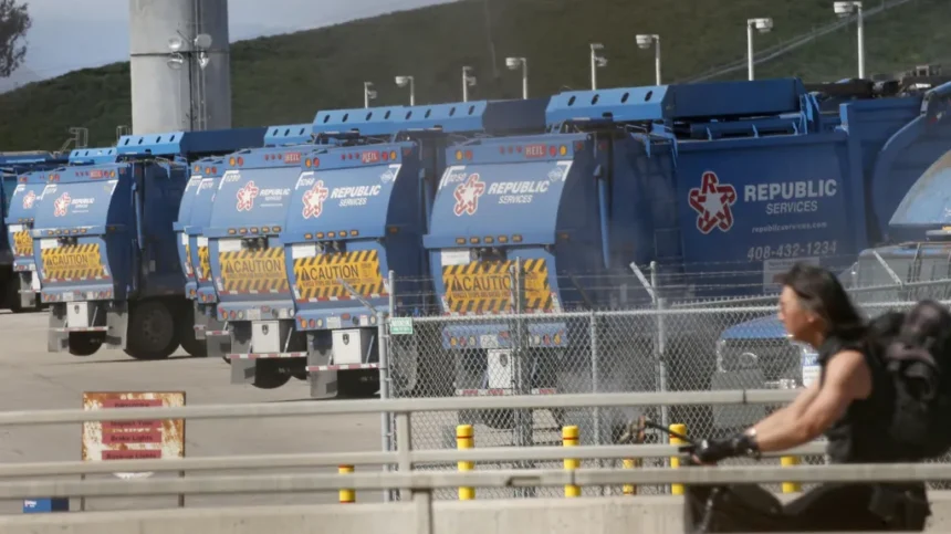 The Mercury News via Getty Images Blue rubbish trucks lined up at Newby Island landfill. A cyclist is in the foreground.