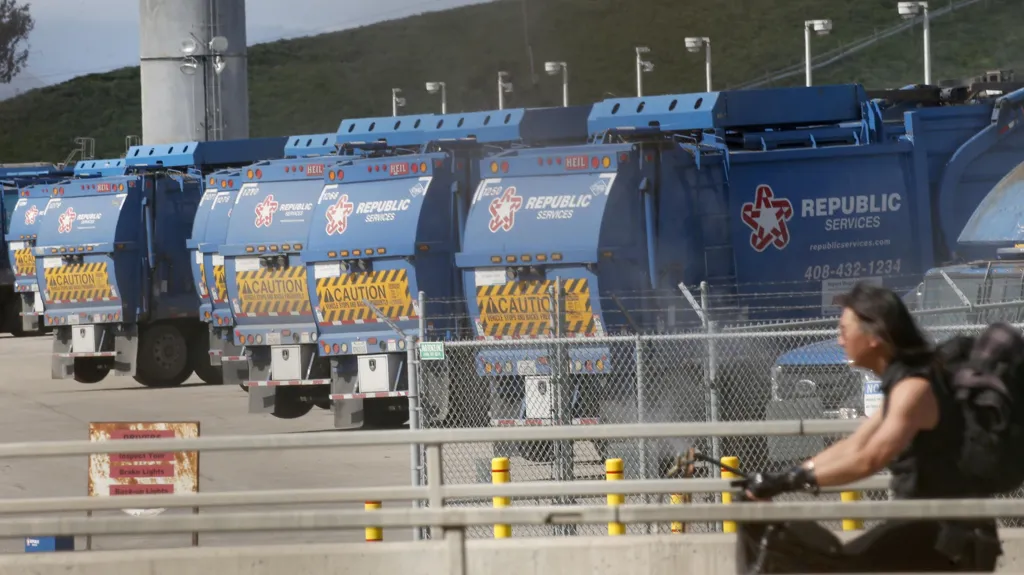 The Mercury News via Getty Images Blue rubbish trucks lined up at Newby Island landfill. A cyclist is in the foreground.