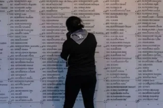 AFP via Getty Images A woman stands in front of list of names of people killed during the 1994 Rwanda genocide