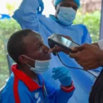 EPA/Shutterstock A man getting checked by a health professional who holds an implement up to him