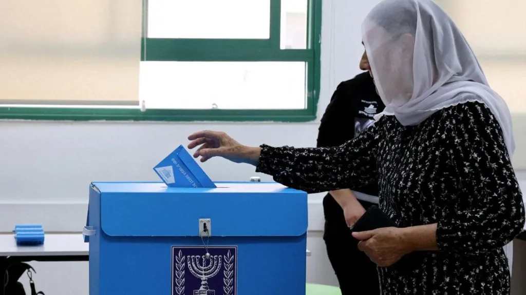 Reuters A woman wearing a headscarf puts a ballot paper in a ballot box in Israel's general election (27/1026)/