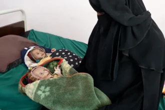 Lee Durant/BBC Raad Hassan is held by his mother Lina, as his twin sister Raghad lies beside him on a bed at a hospital in Aden, Yemen