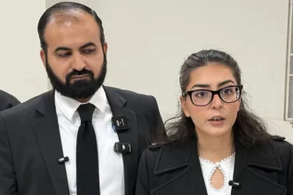 Getty Images A man with a beard in a black suit and tie, standing next to a woman in a black coat and glasses
