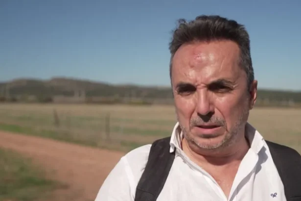 Reuters A man with short hair and a beard - with a bruise on his forehead - speaks to the media; he is wearing a white shirt with the black straps of what appears to be a backpack visible