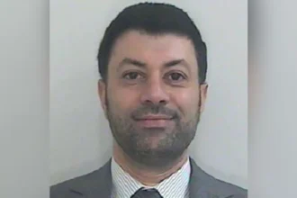 HMRC Image shows a Passport-style photo of Arif Patel, who has short dark hair, a short dark beard, and is wearing a grey suit with a grey and white striped shirt and grey tie.