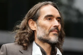 Press Association Russell Brand in a grey suit and open-necked white shirt arriving at court