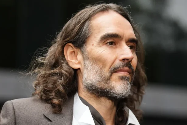 Press Association Russell Brand in a grey suit and open-necked white shirt arriving at court