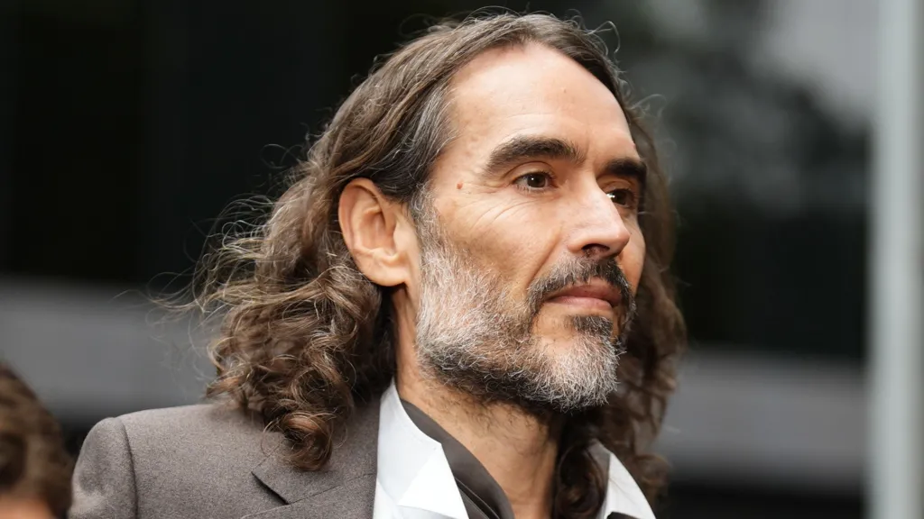 Press Association Russell Brand in a grey suit and open-necked white shirt arriving at court